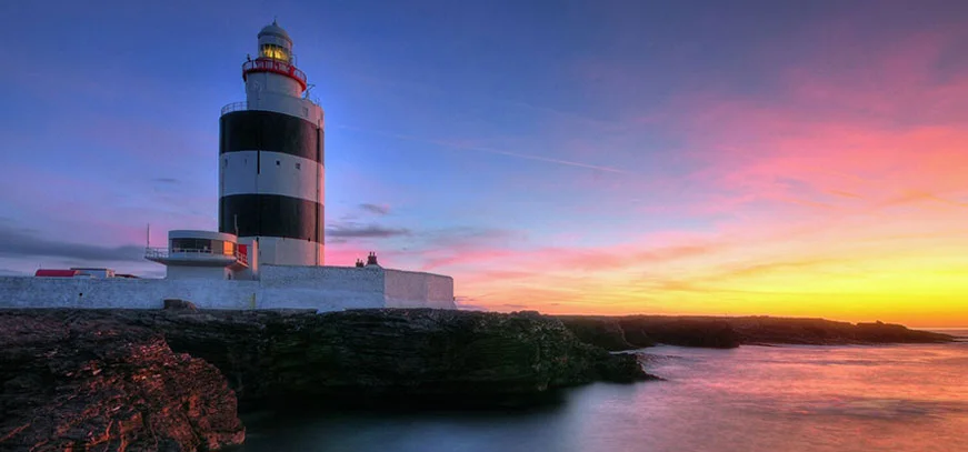 Hook Lighthouse beside the sea at sunset